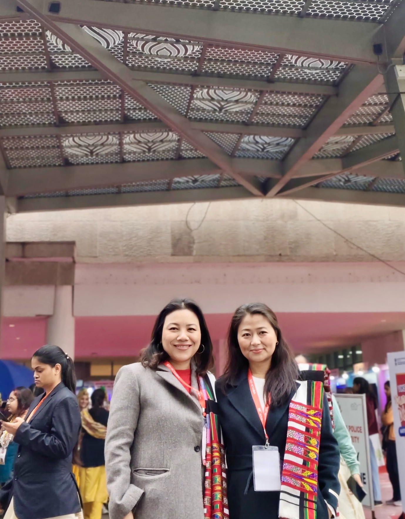 A couple of women standing under a roof

Description automatically generated